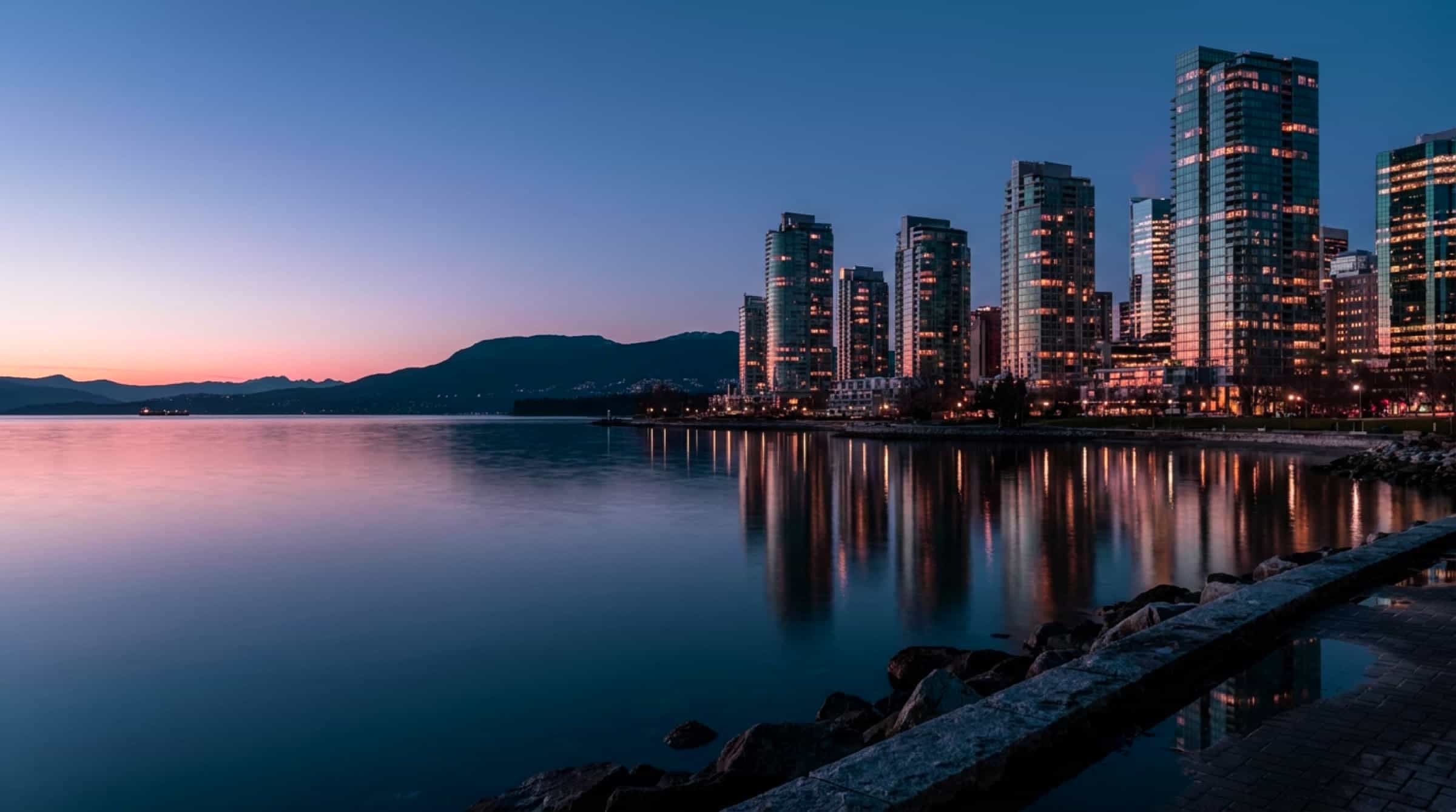 Vancouver's Coal Harbour at dusk, the downtown towers lit and reflected in still water